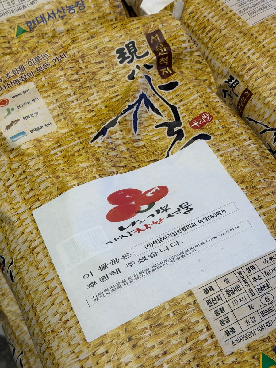 Close-up of donated rice bags labeled with Hanam Business Association Women CEOs donation and social welfare support details.